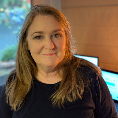 Christina from Tradie Office Help in Australia, wearing a navy tshirt and smiling in a casual office, supporting tradies with invoicing and admin.