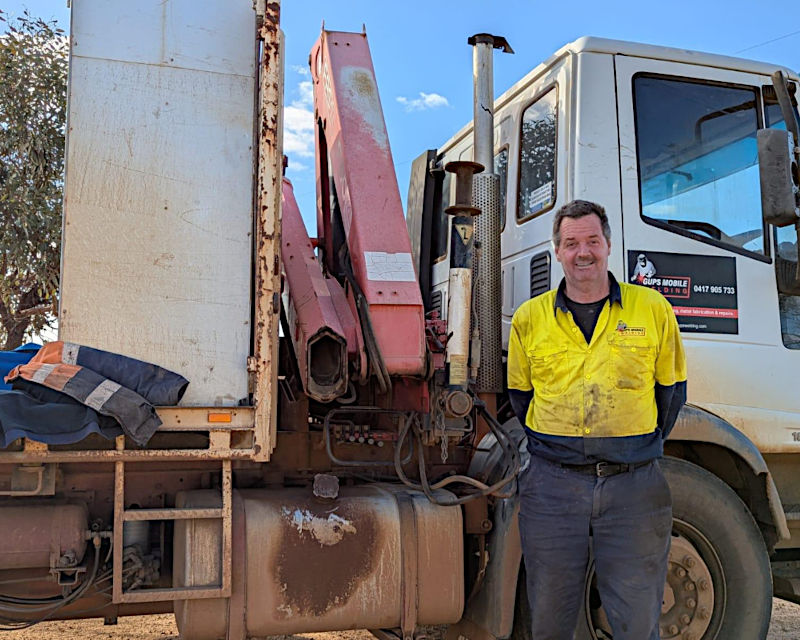 Boilermaker tradie standing near his work truck after finishing the day, having sent job details to Tradie Office Help for invoicing.